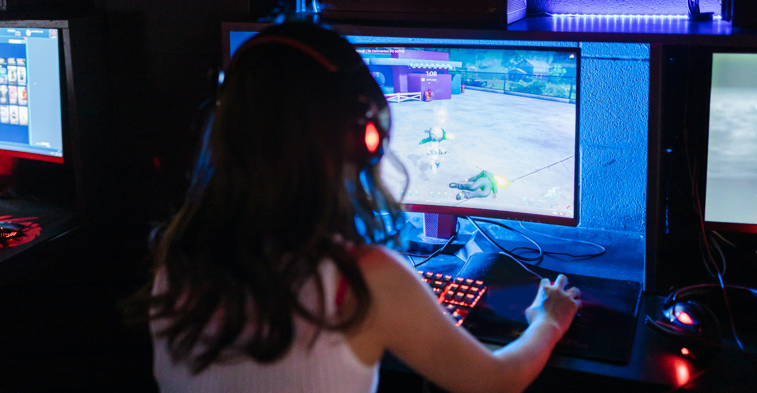 Eine Frau in einem dunklen Raum spielt an ihrem PC.