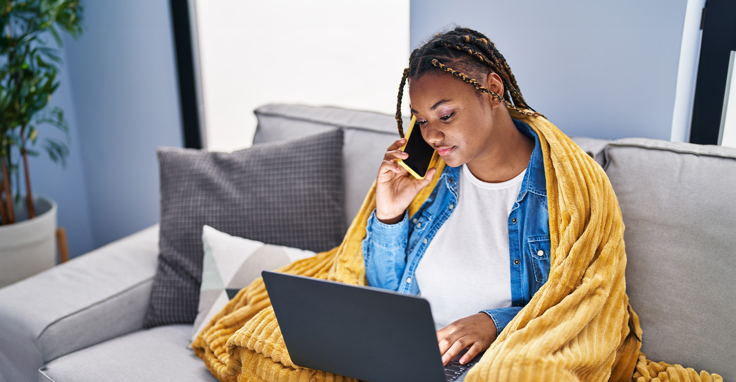 spezialisierte-beratung-header-c-shutterstock BIPoC telefoniert und schaut auf einen Laptop.
